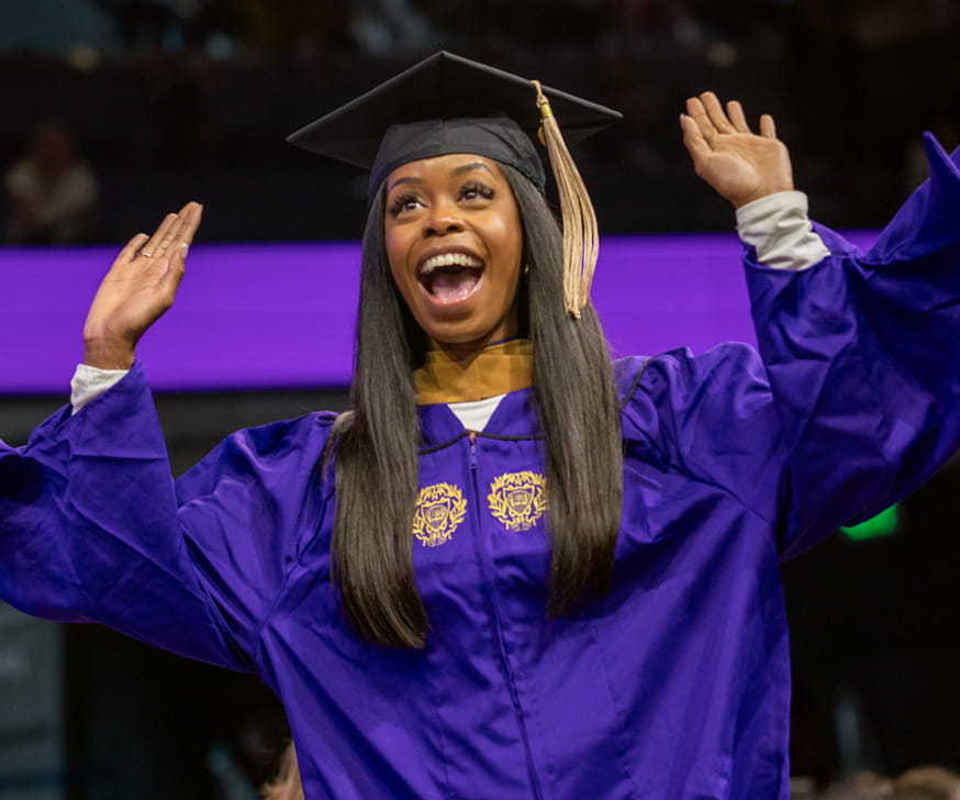 A Kellogg graduate celebrates while walking across the stage at convocation 