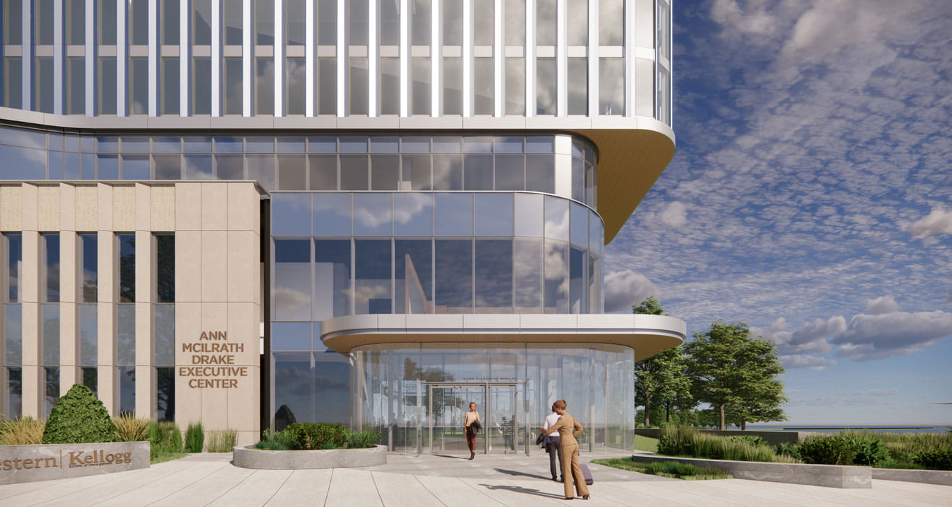 Several people in suits walking into the glass entrance of the Ann McIlrath Drake Executive Center. In the background there's a blue sky with white and grey clouds and trees beside the building.