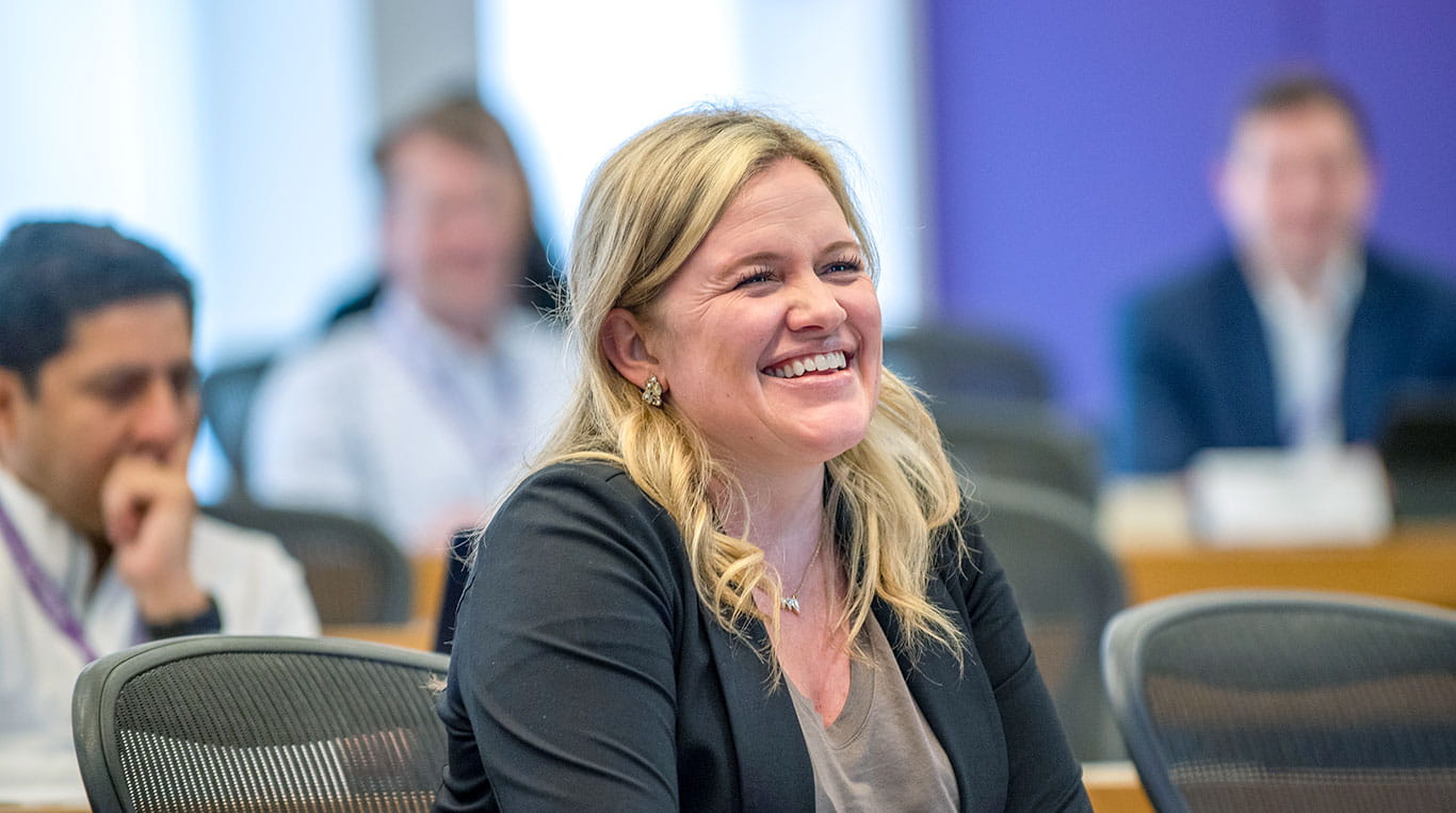 A female student sits in the front row of a classroom smiling