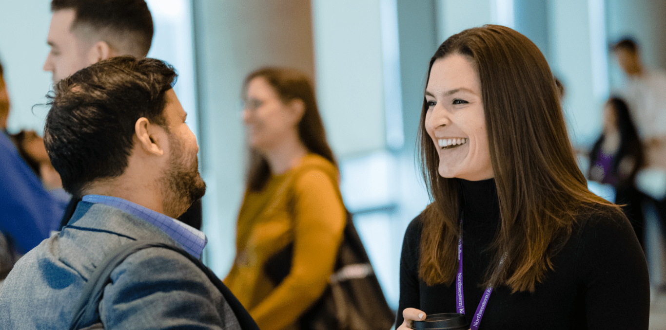 Two MBA students chat in a hallway.