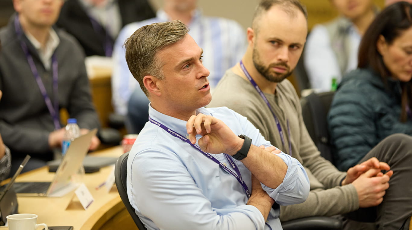 A Kellogg student wearing a blue dress shirt and purple lanyard participates in the Healthcare Deep Dive course.