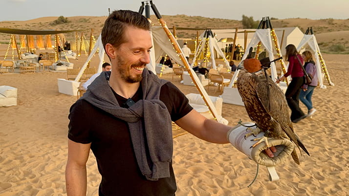 Roman holding a falcon in a desert near Dubai.