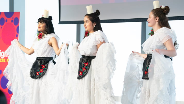 Three women performing a cultural dance from Mexico