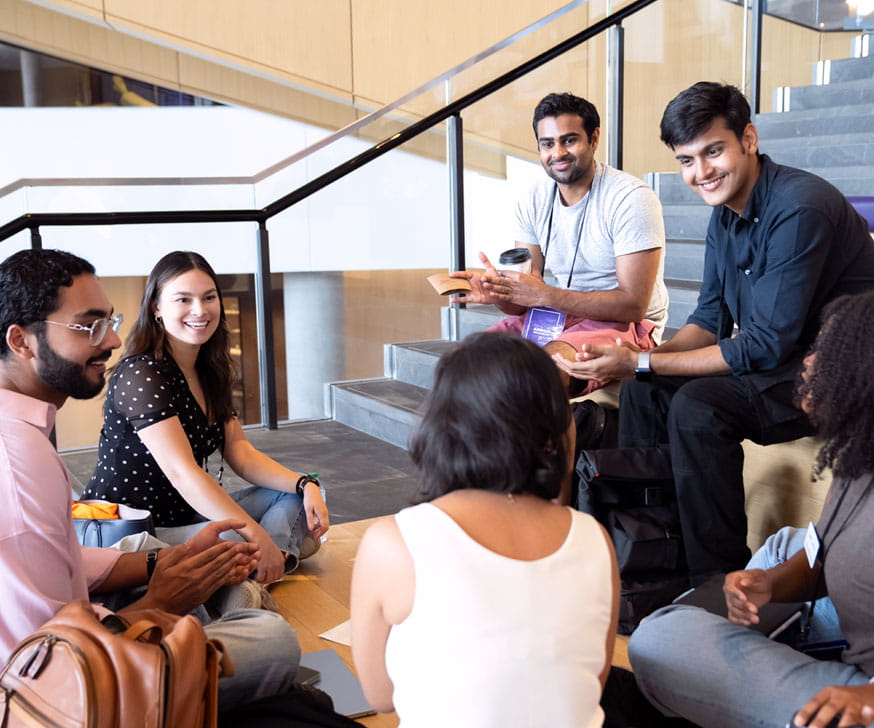 Business students at Kellogg sitting around on stairs at the Global Hub