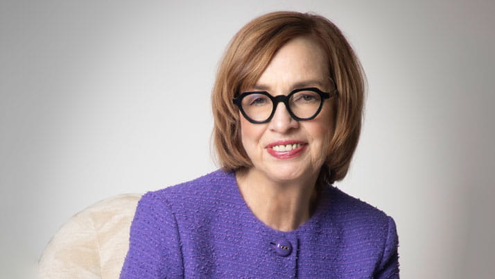 Women wearing black glasses and a purple dress jacket